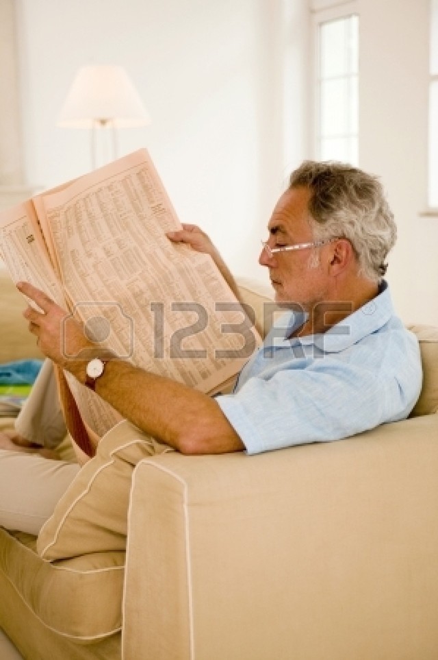 mature close up mature photo man close side sofa reading newspaper intune