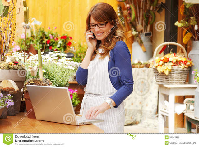 mature photos mature photos woman small using business store take shop orders smiling flower owner laptop telephone florist