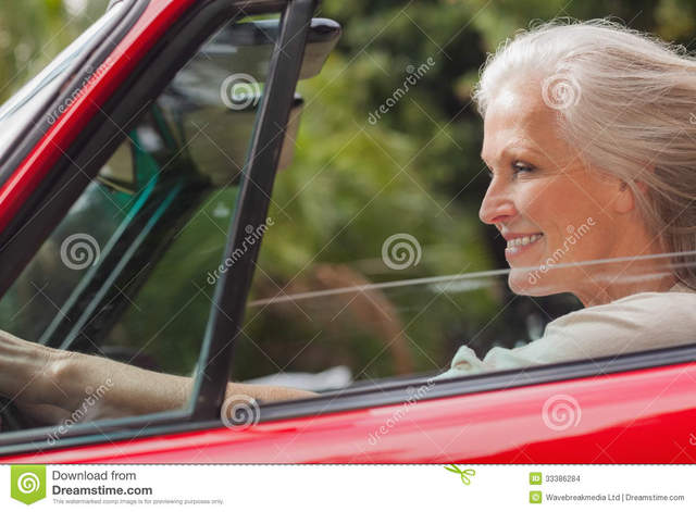 red mature mature woman red sunny stock day driving smiling convertible