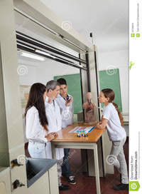 mature teacher teacher experimenting mature students looking him desk lab male student using computer classroom