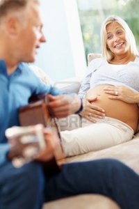 wife mature logos mature man plays guitar his pregnant wife home photo