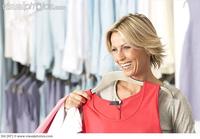 red mature photo mature blonde woman shopping clothes shop holding red vest coathanger smiling