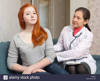 teen and mature comp mature physician palpates behind teen patient focus girl stock photo