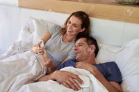 wife mature warrengoldswain happy mature smiling husband wife couple looking mobile cell phone laying bed stock photo